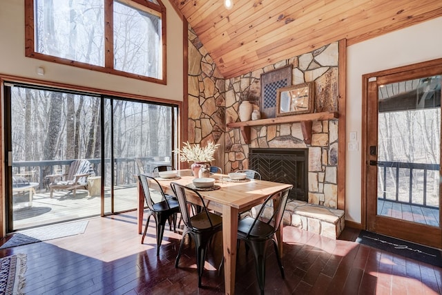 dining room with high vaulted ceiling, a stone fireplace, wood-type flooring, and wood ceiling