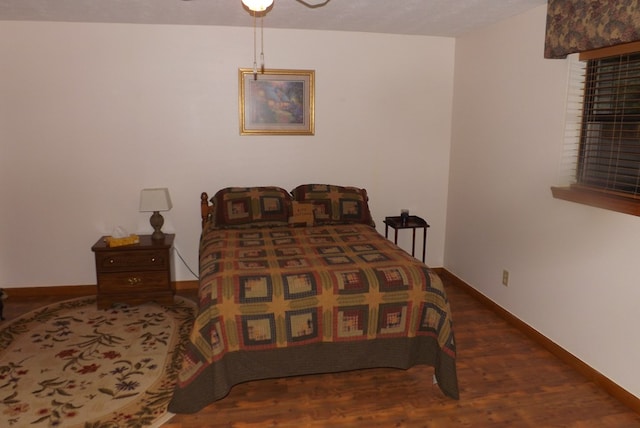 bedroom with dark hardwood / wood-style flooring and ceiling fan