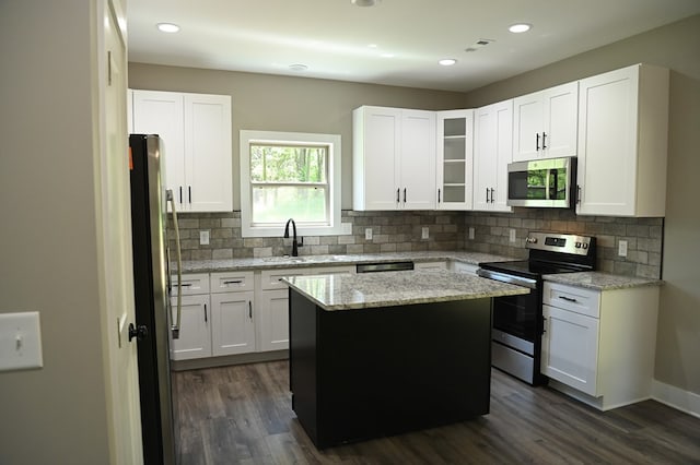 kitchen with appliances with stainless steel finishes, dark hardwood / wood-style flooring, a center island, and white cabinets