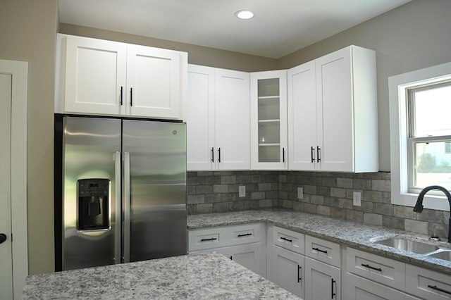 kitchen featuring sink, tasteful backsplash, white cabinetry, and stainless steel refrigerator with ice dispenser