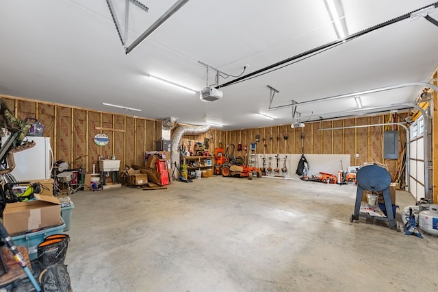 garage featuring sink, a garage door opener, electric panel, and white fridge