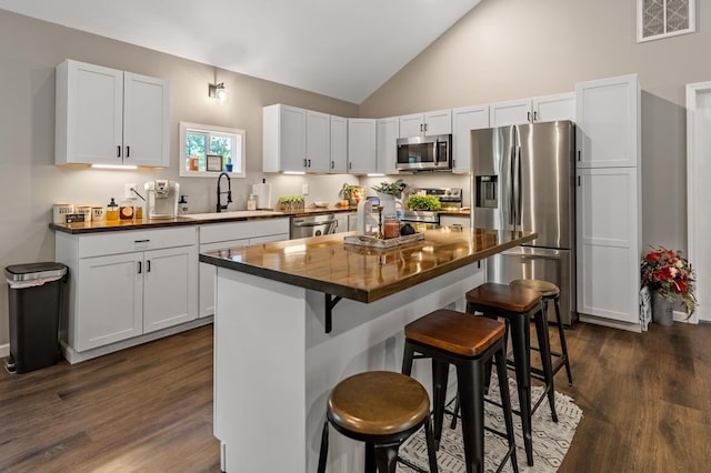 kitchen with a breakfast bar, sink, white cabinets, a center island, and stainless steel appliances