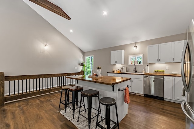 kitchen featuring butcher block countertops, stainless steel appliances, a center island, and white cabinets