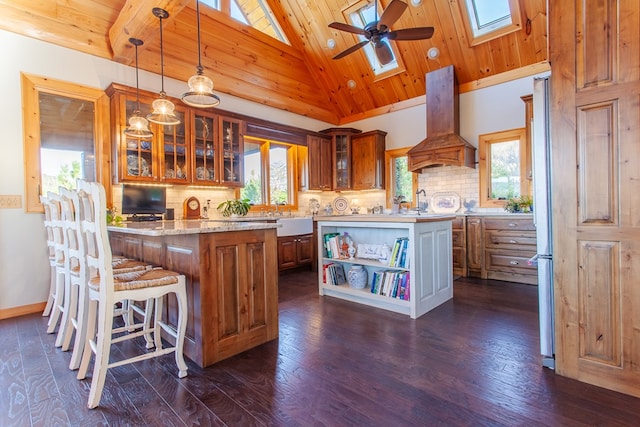 kitchen featuring pendant lighting, a center island, a skylight, dark hardwood / wood-style floors, and custom range hood