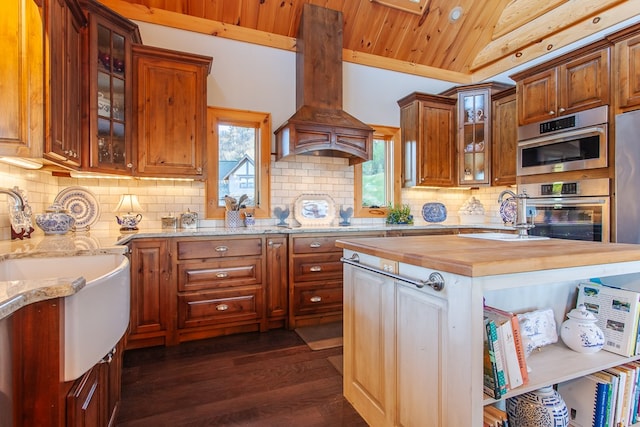 kitchen with wood counters, custom exhaust hood, stainless steel oven, vaulted ceiling, and dark wood-type flooring