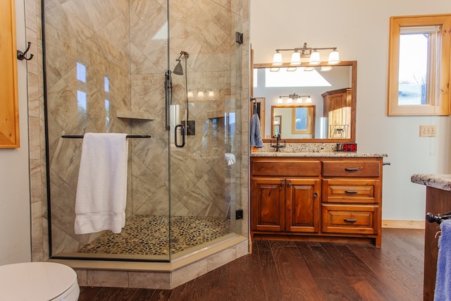 bathroom featuring wood-type flooring, vanity, toilet, and a shower with door