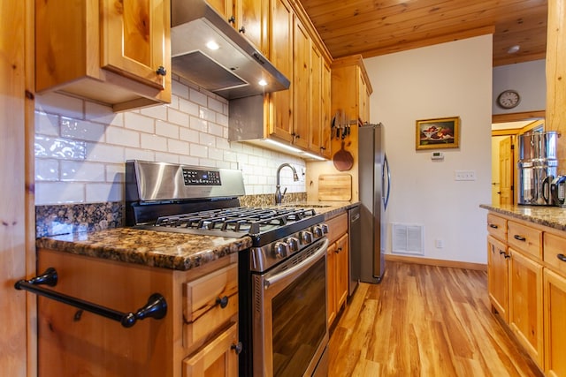 kitchen with tasteful backsplash, dark stone counters, stainless steel appliances, sink, and light hardwood / wood-style flooring