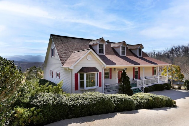 cape cod home featuring covered porch