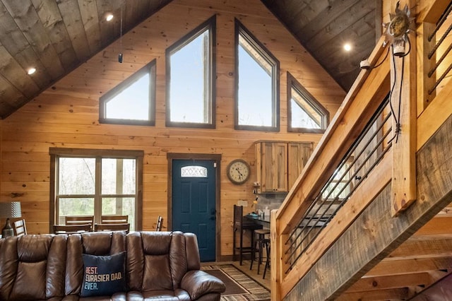 living room featuring high vaulted ceiling, wooden walls, and wood ceiling