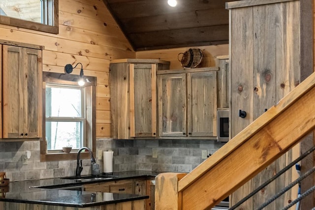 kitchen with wooden walls, tasteful backsplash, sink, and lofted ceiling