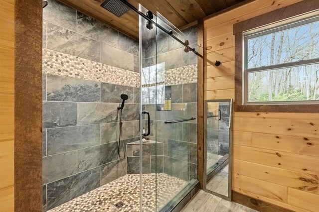 bathroom with wooden walls, a shower with shower door, and wooden ceiling