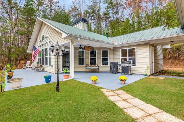 rear view of property with ceiling fan, a lawn, and a patio