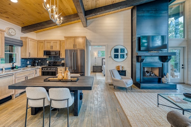 kitchen with light wood-type flooring, light brown cabinets, vaulted ceiling with beams, and stainless steel appliances