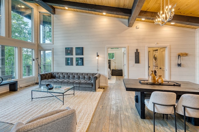 living room with beamed ceiling, wooden ceiling, stacked washer and clothes dryer, and light wood-style flooring
