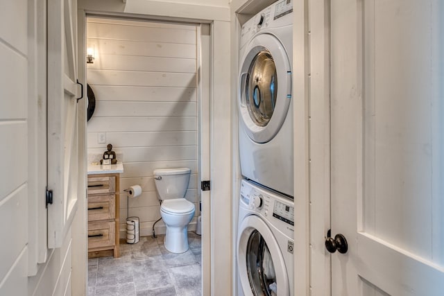 bathroom featuring stacked washer and clothes dryer and toilet