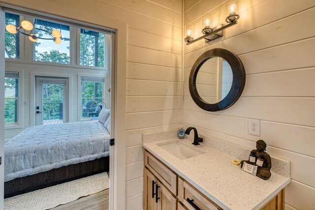 bathroom featuring wooden walls, vanity, and ensuite bathroom