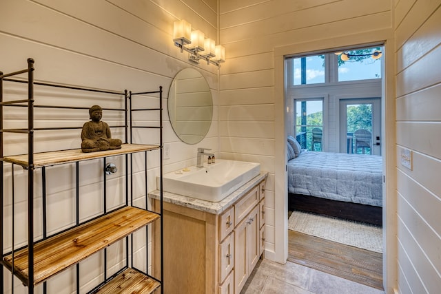 bathroom featuring vanity, ensuite bath, and wooden walls