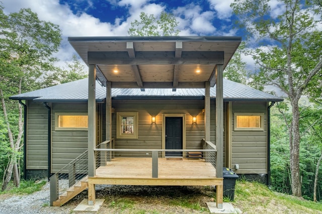 back of house featuring covered porch and metal roof