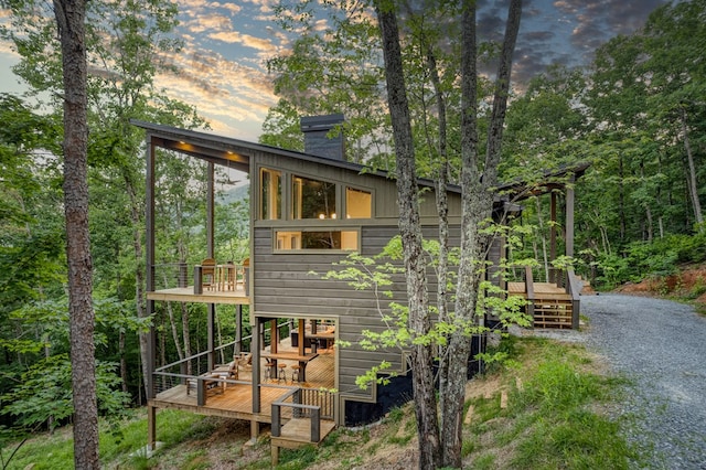 back of house at dusk featuring a deck and a chimney