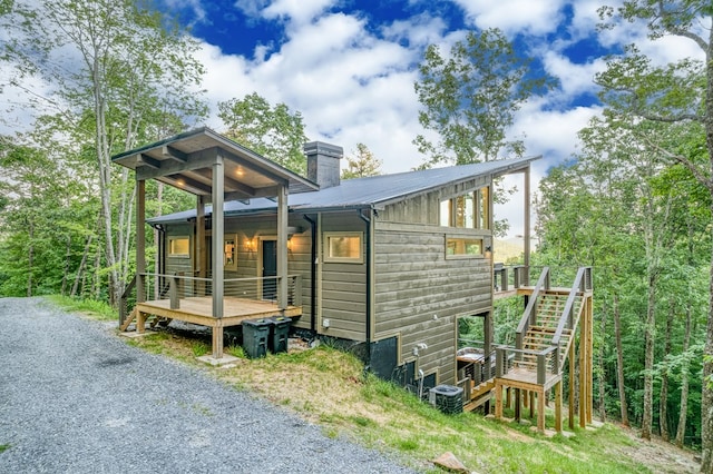rear view of property featuring stairway, metal roof, a chimney, and cooling unit