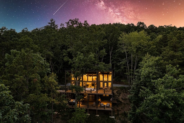 rear view of property featuring a view of trees and a wooden deck