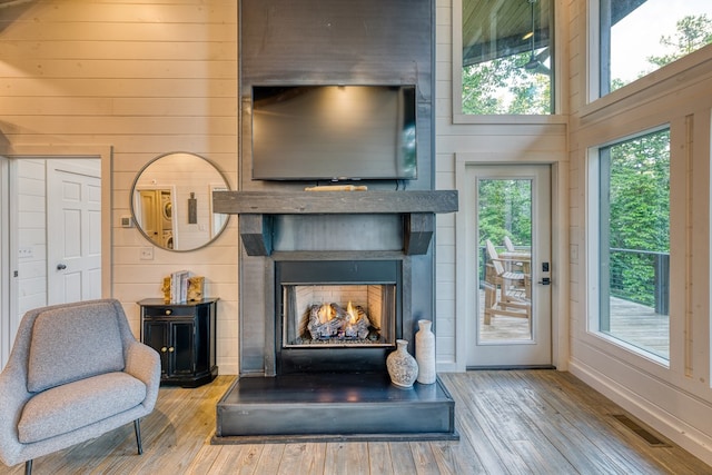 living room with visible vents, wood walls, baseboards, and wood finished floors