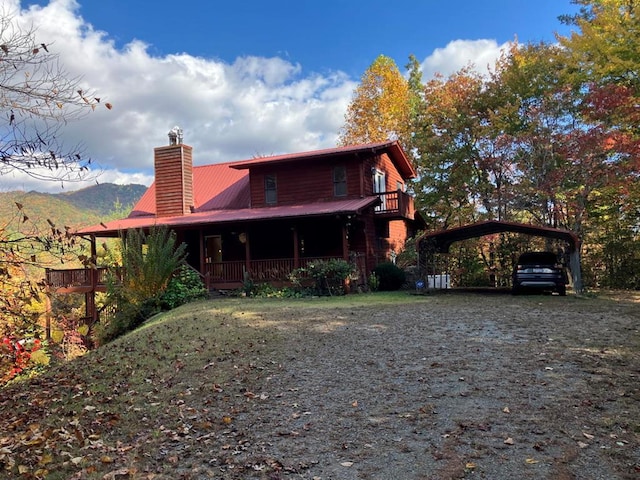 rear view of property featuring a mountain view, covered porch, and a carport