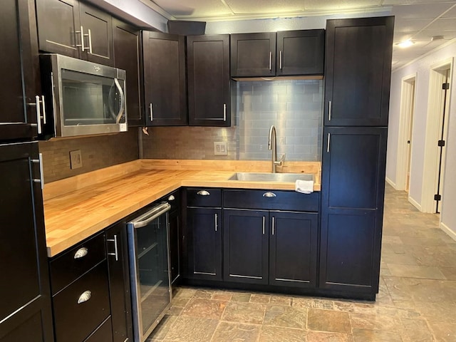 kitchen featuring sink, wood counters, backsplash, and beverage cooler