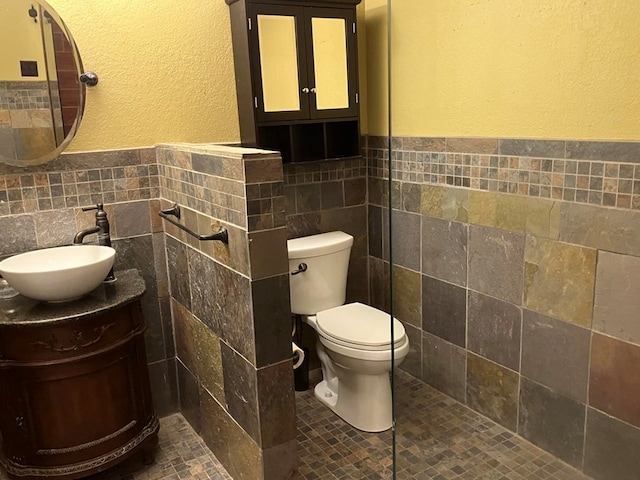 bathroom featuring tile walls, vanity, and toilet