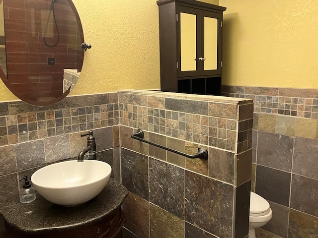 bathroom with toilet, walk in shower, vanity, and tile walls