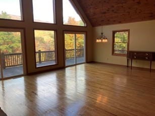 unfurnished living room featuring a healthy amount of sunlight, a high ceiling, and hardwood / wood-style floors