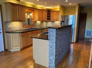 kitchen featuring sink, a center island, wood-type flooring, and backsplash