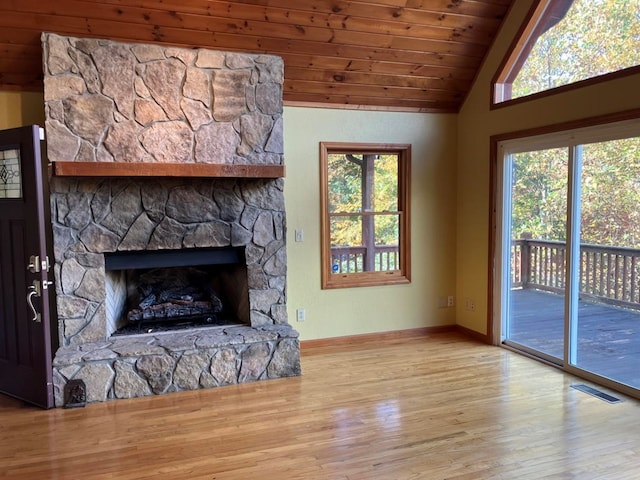 unfurnished living room with a stone fireplace, lofted ceiling, wooden ceiling, and a wealth of natural light