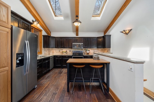 kitchen with backsplash, kitchen peninsula, sink, appliances with stainless steel finishes, and dark brown cabinetry