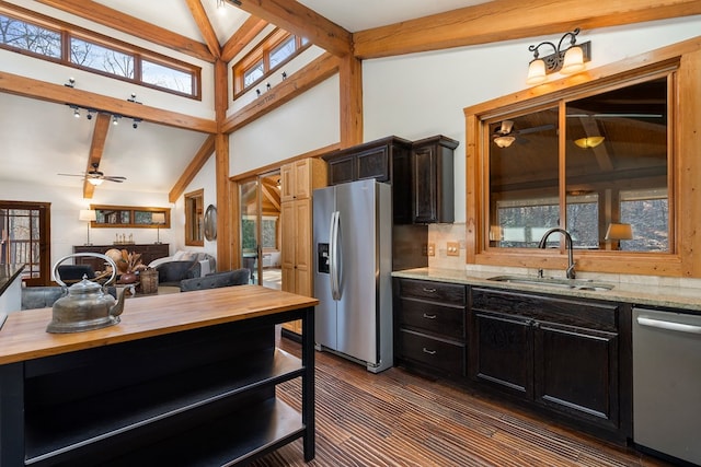 kitchen featuring beamed ceiling, light stone countertops, sink, and appliances with stainless steel finishes