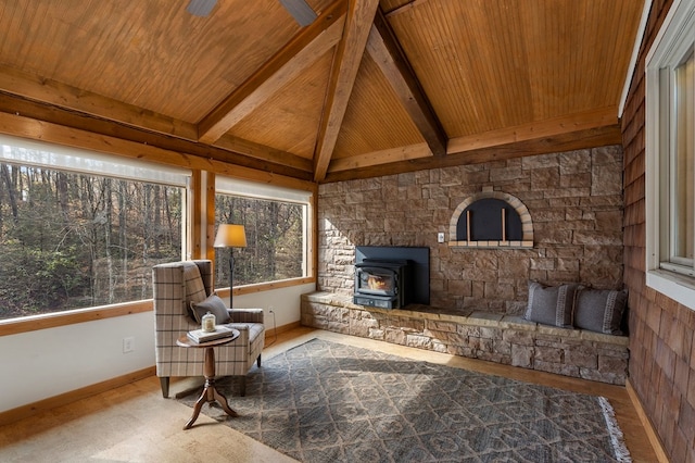 sunroom / solarium featuring vaulted ceiling with beams, a wood stove, ceiling fan, and wood ceiling