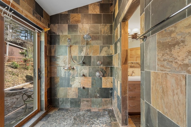 bathroom with sink, tile walls, a tile shower, and vaulted ceiling