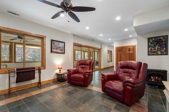 living room with ceiling fan and a wood stove