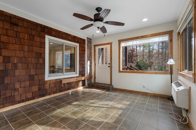 interior space featuring dark tile patterned flooring, ceiling fan, and an AC wall unit