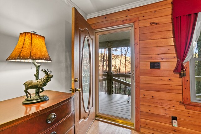 doorway with wood walls, ornamental molding, and light hardwood / wood-style flooring