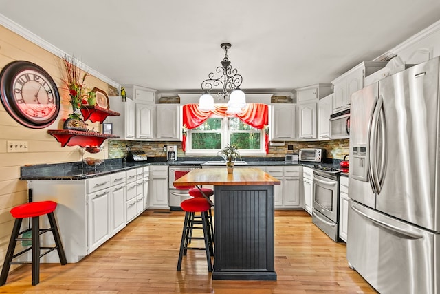 kitchen featuring a kitchen breakfast bar, stainless steel appliances, a notable chandelier, a center island, and white cabinetry