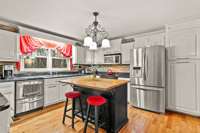 kitchen featuring white cabinets, a center island, stainless steel appliances, and butcher block counters