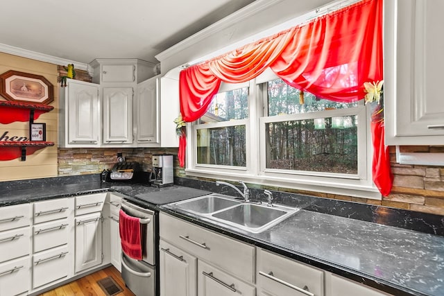 kitchen with backsplash, white cabinets, sink, light wood-type flooring, and ornamental molding