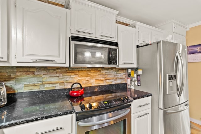 kitchen with white cabinets, dark stone countertops, ornamental molding, tasteful backsplash, and stainless steel appliances