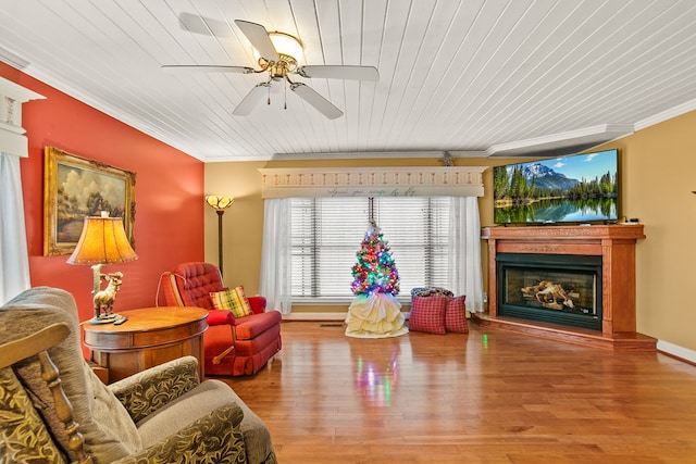 living area with ceiling fan, wooden ceiling, wood-type flooring, and ornamental molding