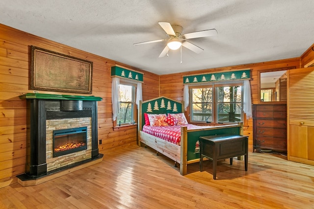 bedroom featuring light hardwood / wood-style floors, multiple windows, wood walls, and ceiling fan