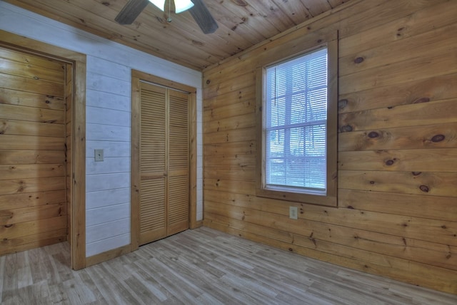 unfurnished bedroom featuring wooden walls, light hardwood / wood-style flooring, ceiling fan, and wood ceiling