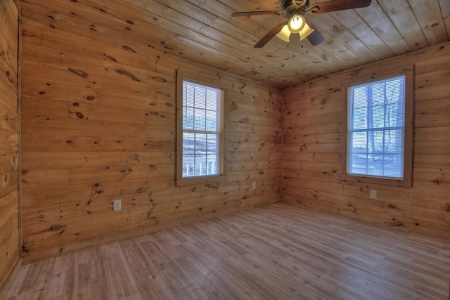 empty room with ceiling fan, wood walls, light wood-type flooring, and wooden ceiling