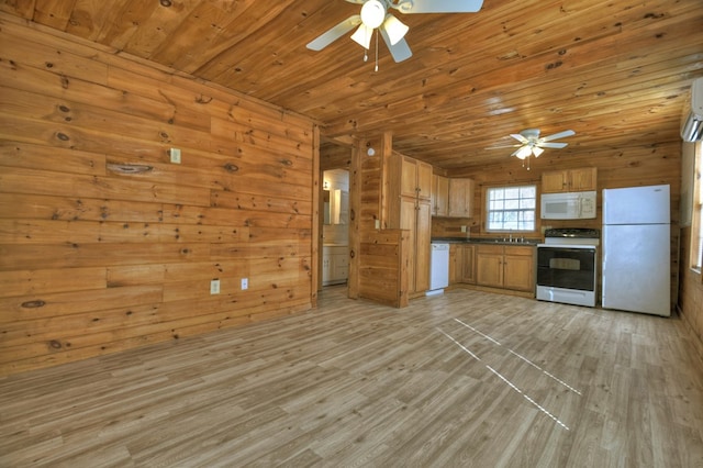 kitchen with wood walls, white appliances, sink, ceiling fan, and light wood-type flooring