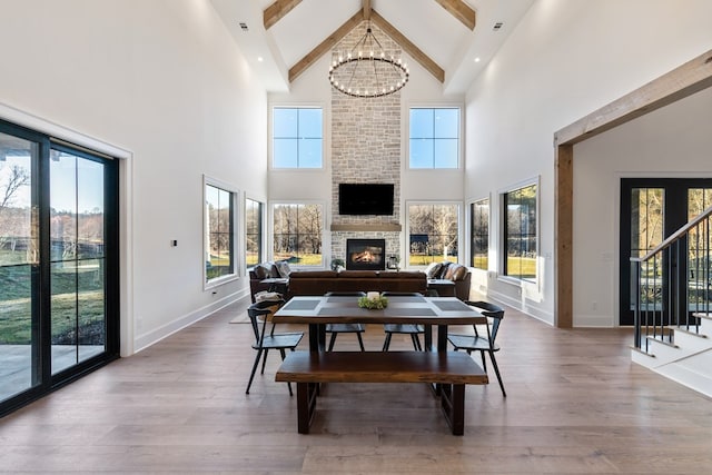 dining area featuring a notable chandelier, a fireplace, stairs, and wood finished floors